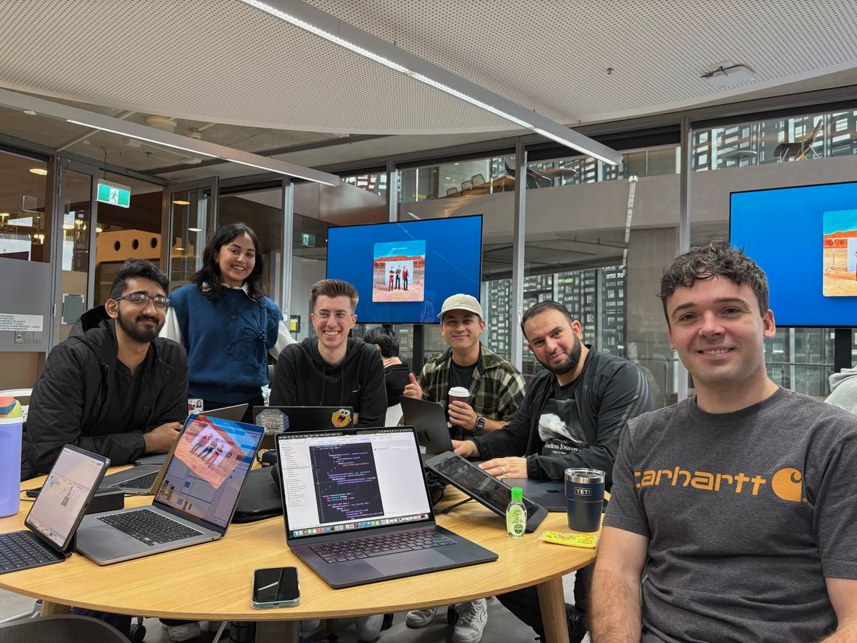 Noah with other mentors and members of a cohort around a table of laptops.
