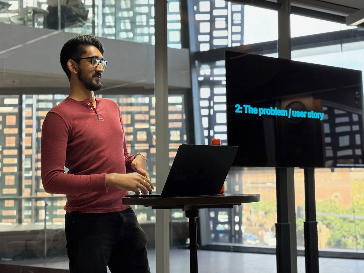 Noah presenting to a cohort, beside a screen reading “2: The problem / user story”.