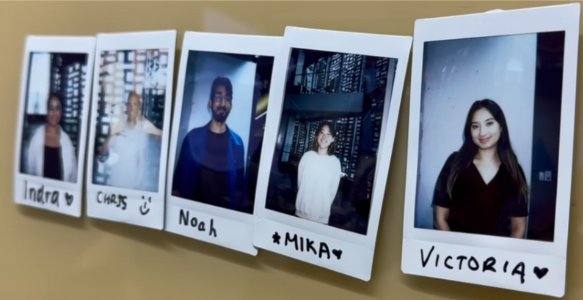 Polaroid photos of the team pinned to a wall, labelled Indra, Chris, Noah, Mika and Victoria.