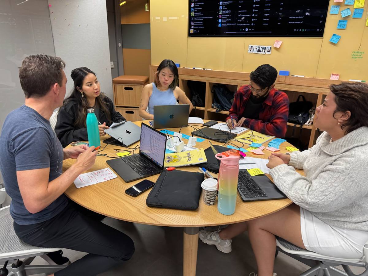 The team working around a table with laptops, notebooks and sticky notes.